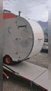 a white trailer with red wheels is sitting on a ramp in a parking lot