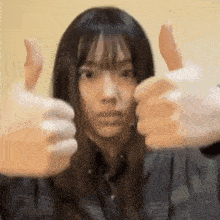 a woman is giving a thumbs up sign with her hands .