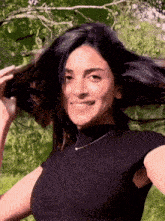 a woman in a black top holds her hair in the air
