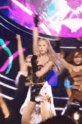 a group of women are dancing on a stage in front of a crowd .