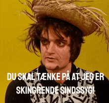 a man wearing a straw hat with the words du skal tænke på at jeg er skingrendele sindssyg