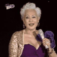a woman in a purple dress is holding a microphone