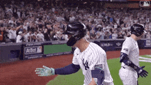 a baseball player wearing a ny yankees uniform is walking on the field