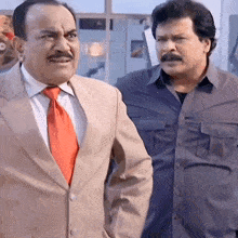 two men are standing next to each other and one has a mustache