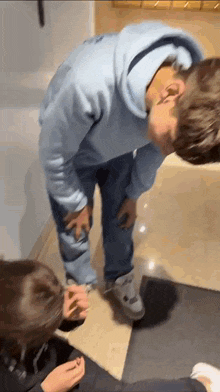 a man in a blue hoodie is kneeling down next to a girl