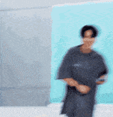 a blurry picture of a man in a black shirt dancing in front of a blue wall .
