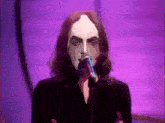 a man singing into a microphone with his face painted white