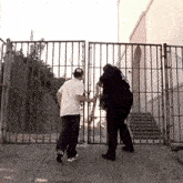 two men are standing in front of a chain link fence holding a stick