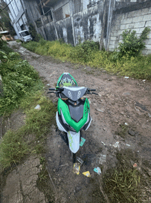 a green and white motorcycle is parked on the side of the road