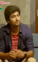 a man is sitting on a couch with his hands folded and a watch on his wrist .