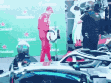 a man in a red suit is holding a trophy in front of a green wall that says heineken