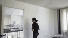 a woman in a black shirt is standing in a room with the words made in animatica on the bottom