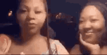 two women are standing next to each other in a car and smiling .