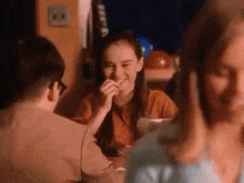 a group of people are sitting at a table eating food and talking .