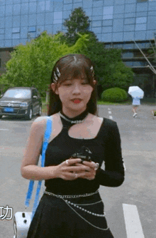 a woman standing in front of a building holding a cellphone