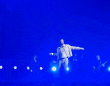 a man singing into a microphone on a stage with a blue light behind him