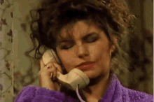 a woman is talking on a telephone with her eyes closed .