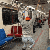 a man is hanging from the ceiling of a subway car with a sign that says ' spike lee ' on it