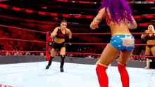 two women are wrestling in a wrestling ring . one of the women is wearing a wonder woman outfit .