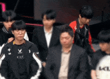 a group of people are standing in a room with a man in a suit standing in the middle .