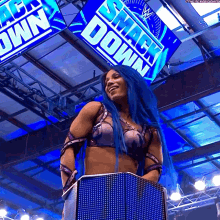 a woman with blue hair is smiling in front of a smack down sign