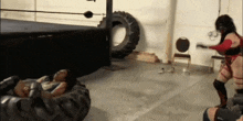 a woman is wrestling another woman in a wrestling ring while a tire is in the background .
