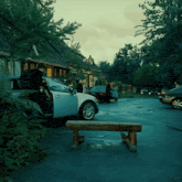 a white car is parked in a parking lot with people standing around
