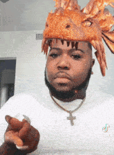 a man wearing a dragon hat and a cross necklace is pointing at the camera