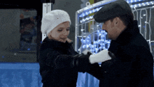a man and a woman are hugging each other in front of christmas lights