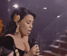 a woman in a black dress is talking into a microphone while holding a glass of wine .