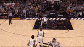 a group of basketball players are playing a game of basketball on a court with a crowd watching .
