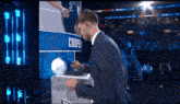 a man in a suit is holding a basketball in front of a sign that says cooper