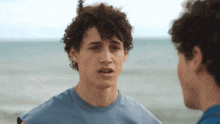 two young men with curly hair are talking to each other