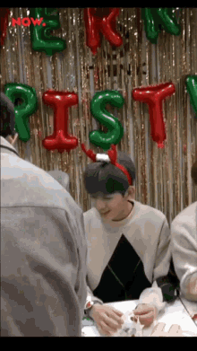 a boy wearing a santa headband stands in front of a christmas decoration
