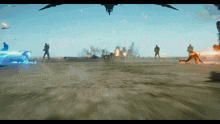 a group of people are standing on a sandy beach in front of a large explosion