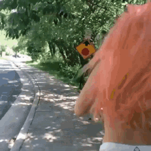 a woman with pink hair is walking down a sidewalk next to a yellow sign that says ' a ' on it