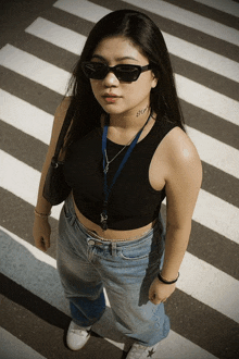 a woman wearing sunglasses and a black tank top has a tattoo on her neck that says " bitch "