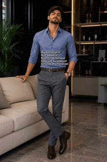 a man in a blue shirt and grey pants is standing next to a couch