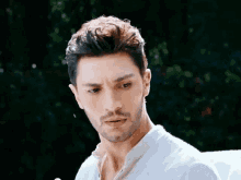 a man with a beard and a white shirt is looking at the camera