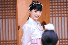a woman wearing a white top and a pink dress with the word korean on the bottom left