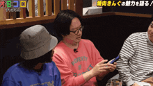 a man wearing a pink shirt that says poverty looks at his phone