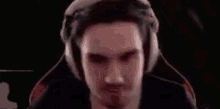 a man is wearing headphones and making a funny face while sitting in a chair .