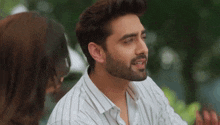 a man with a beard and a striped shirt is talking to a woman .