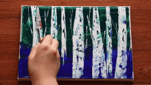 a person is painting a picture of birch trees on a canvas