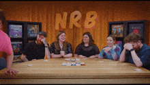 a group of people are sitting around a table with nrb written on the wall behind them