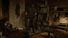 a man standing in a dark room with a picture of a man on the wall behind him