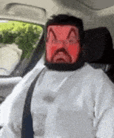a man wearing a red mask is sitting in a car with a seat belt .