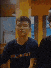 a man wearing a black shirt with the word yogyakarta on it is sitting next to another man .