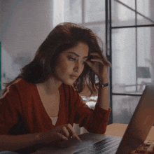 a woman in a red sweater is using a laptop