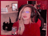 a woman wearing headphones and glasses is sitting in front of a microphone in a red chair .